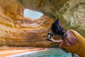 Frau fotografiert eine der Höhlen der Algarve - Algar de Benagil