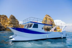 Barco turístico da Discover Tours junto às formações rochosas e águas cristalinas da costa algarvia, num passeio marítimo no Algarve.